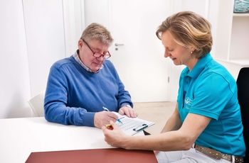 Ärztin hilft einem Patient Dokumente auszufüllen